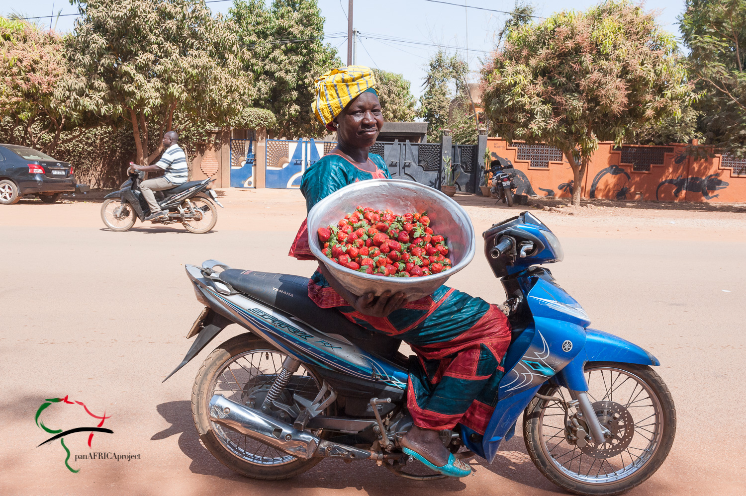 A woman selling strawberries on a motorcycle
