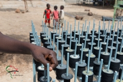 Children standing next to a rack of spindles filled with thread