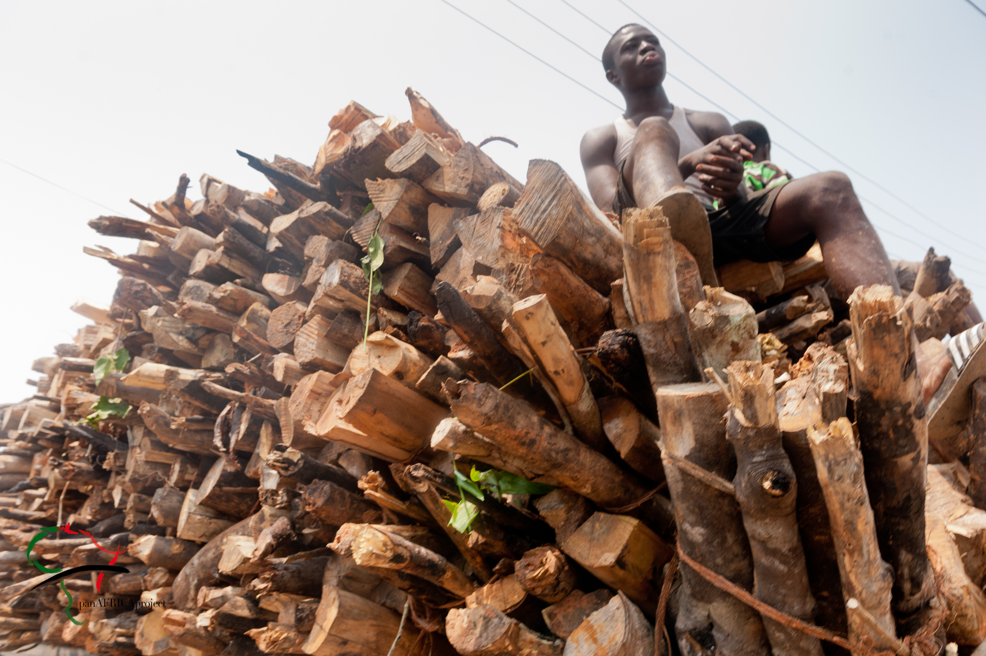 Man sitting on a stack of fire wood in Elmina, Ghana