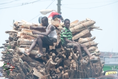 Men sitting on a pile of fire wood in Elmina, Ghana