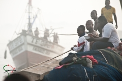 Men sitting on fishing nets in Benya Lagoon Ghana in Elmina, Ghana