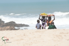 Women walking on the beach with fruit on their head in Winneba, Ghana