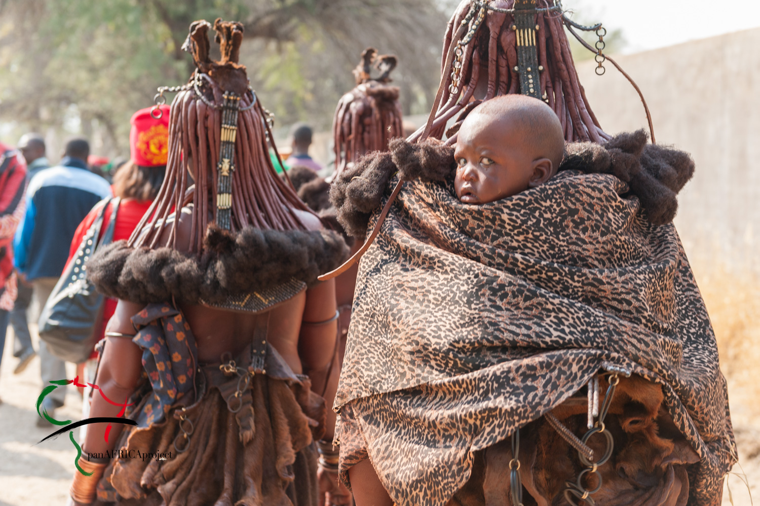 A child being carried on the back of a Himba woman
