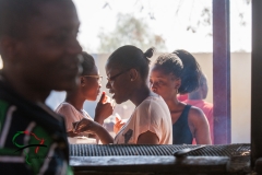Women eating food behind a gril.