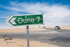 Road sign with car driving in the background.