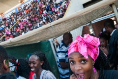 Female students entering stadium with crowd in background.