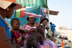 Herero tribe woman sitting in the shade with family