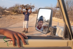Man carrying firewood while child looks in mirror