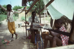 A group of men making fabric on a loom in Kaolack, Senegal