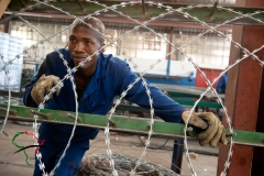Factory worker looking through razor wire