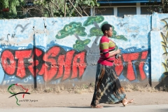 A woman walking by a wall that has graffiti on it