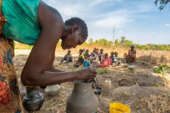 Woman making a pot out of clay as children watch