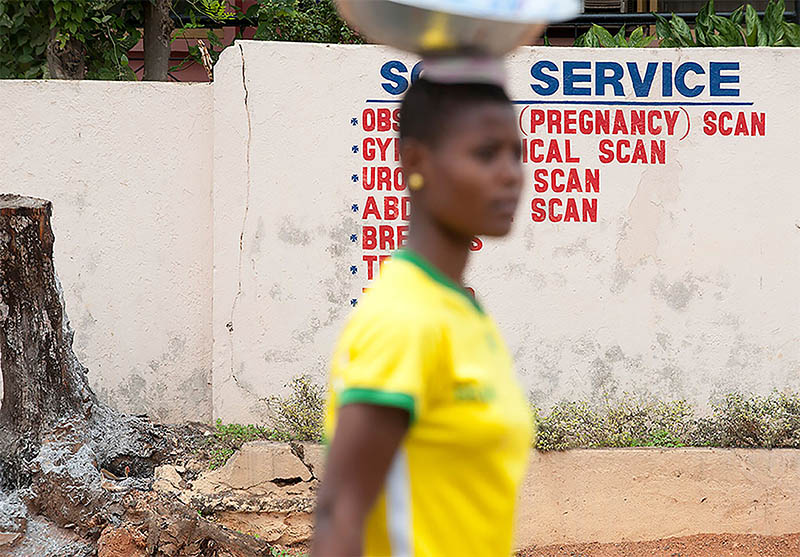 Woman walking in front of a sign for medical clinic in Kumasi