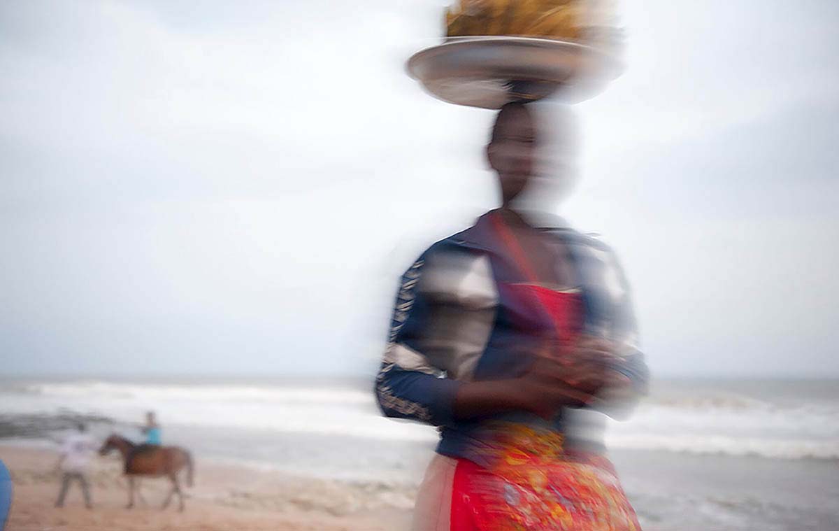 Woman carrying food on her head on the Tawala beach.