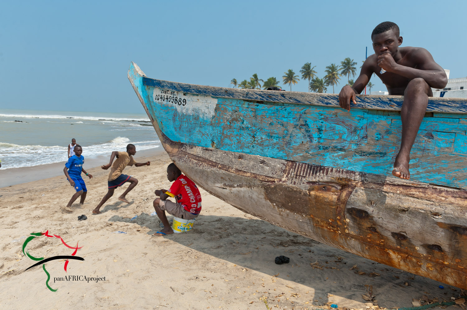 Man sitting in boat while people running on the beach