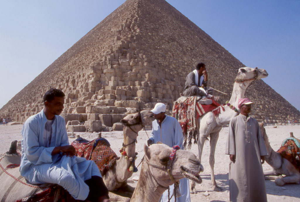 Men with camels in front of the Great Pyramids of Giza