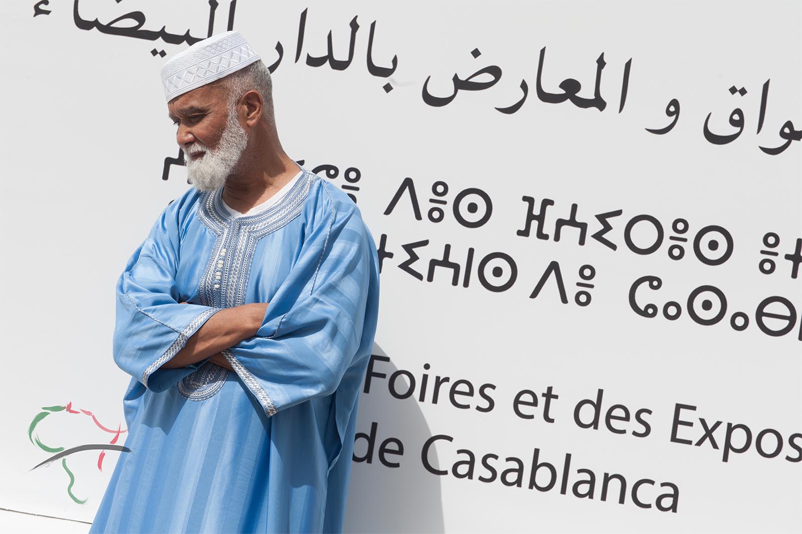 Portrait of man leaning on a wall with Arabic at Hassan II Mosque 